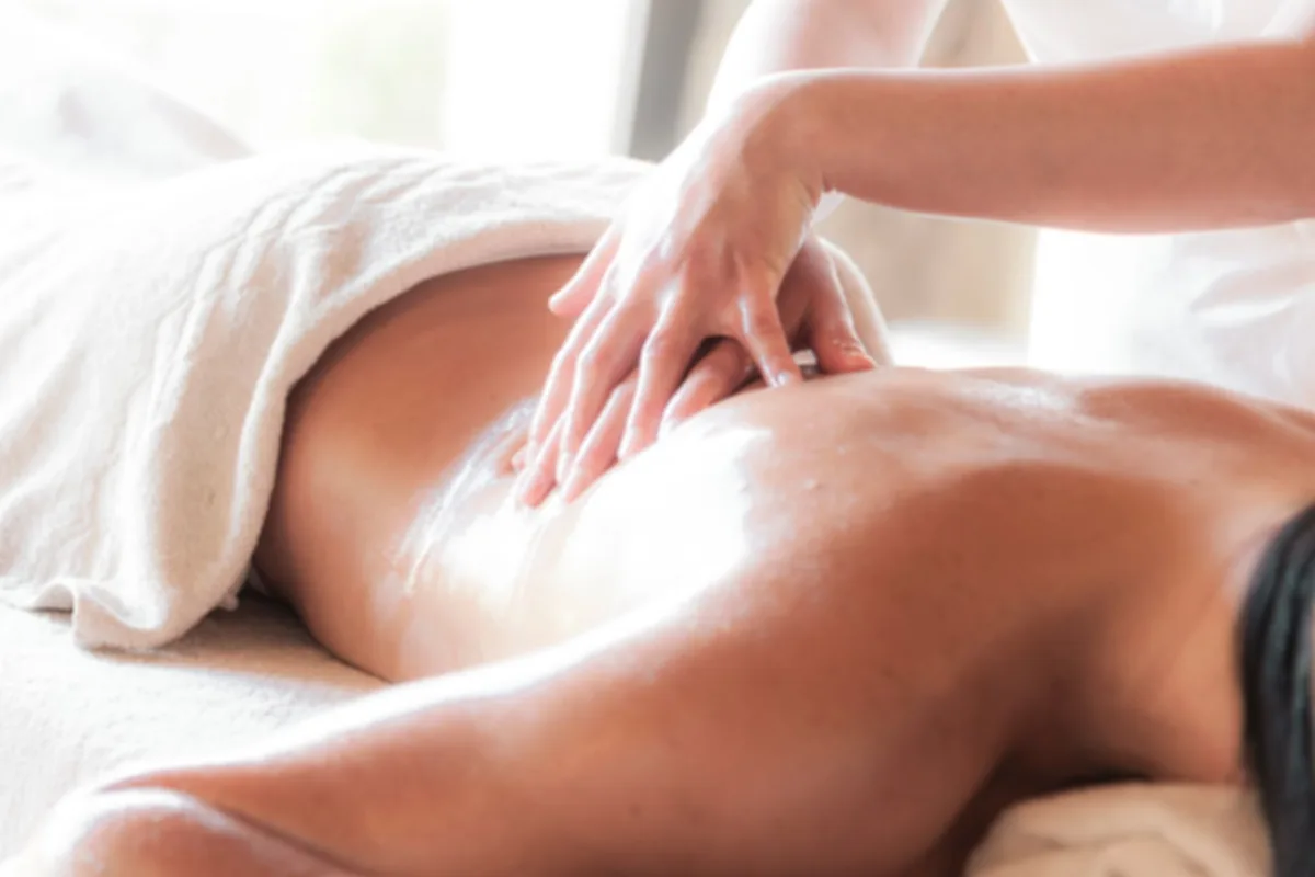 Hands applying essential oil to skin during a therapeutic massage