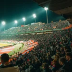 Enthusiastic fans cheering in a packed football stadium during a game