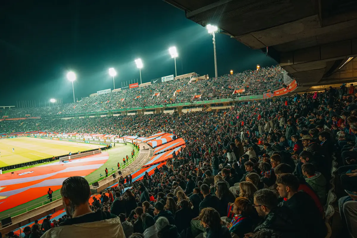 Enthusiastic fans cheering in a packed football stadium during a game