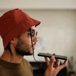 Smartphone screen showing audio waveforms and AI narration interface with headphones on desk