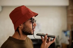 Smartphone screen showing audio waveforms and AI narration interface with headphones on desk