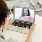 Person receiving online therapy support through video call on laptop