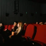 Cinephiles entering a vibrant film festival venue with glowing marquees and eclectic posters lining the walls