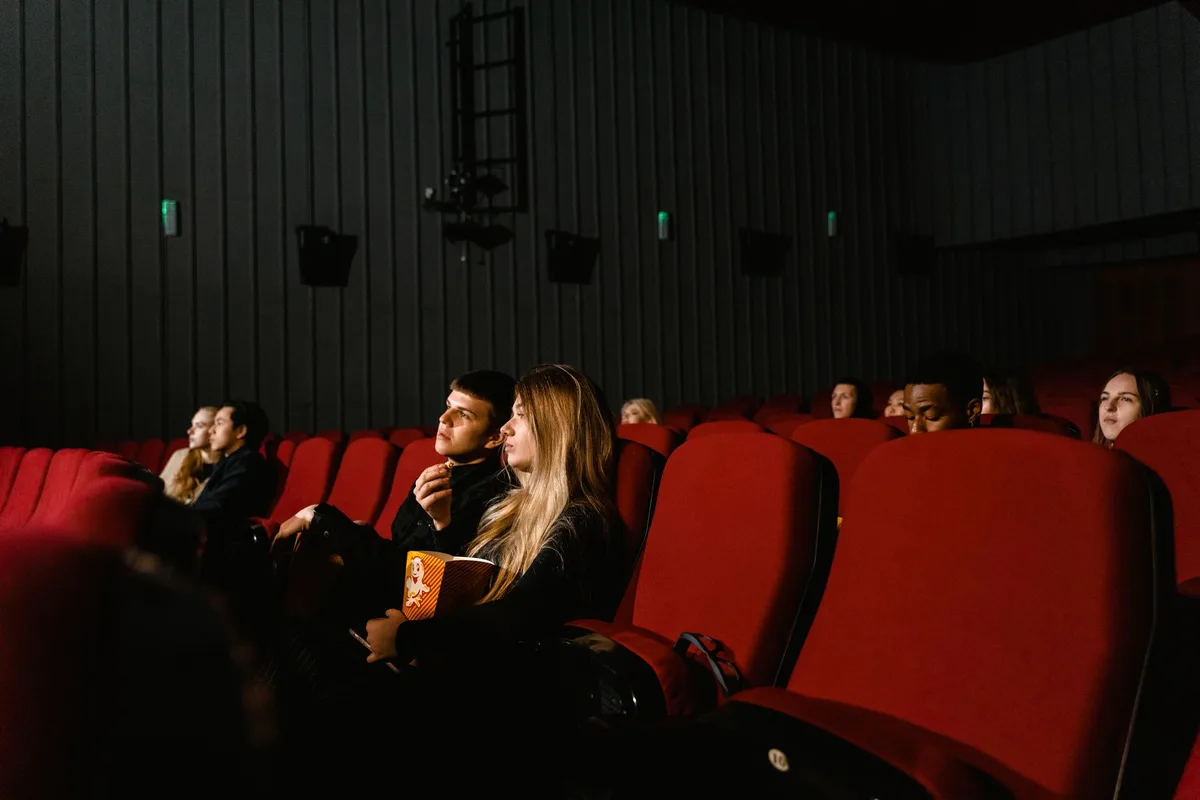 Cinephiles entering a vibrant film festival venue with glowing marquees and eclectic posters lining the walls
