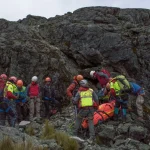Rescue team members in winter gear navigating snow-covered mountain slopes during a high-altitude search operation