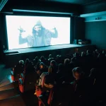 Audience members in silhouette watching a film projection at a cinema festival event