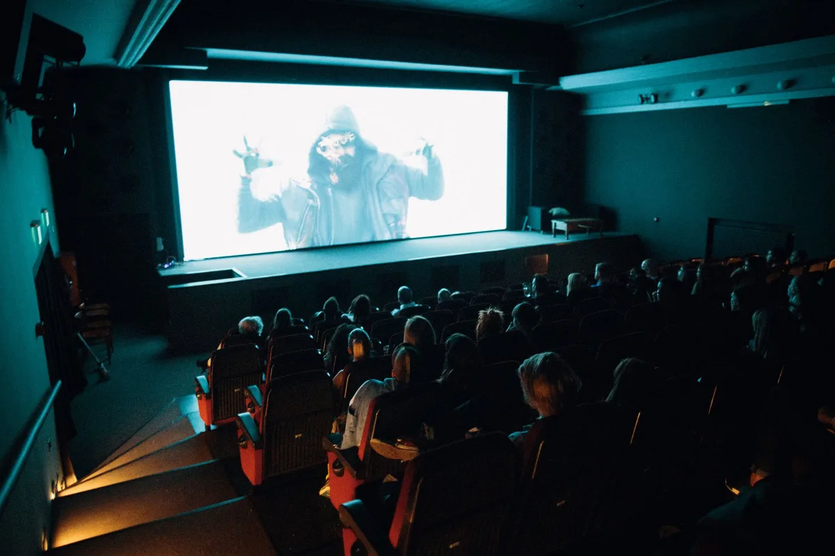 Audience members in silhouette watching a film projection at a cinema festival event