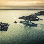 Port facility with cargo ships and strategic planning documents, symbolizing Oman's geopolitical position