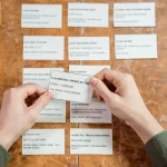 Hands of a collector opening trading card packs at a desk with cards displayed