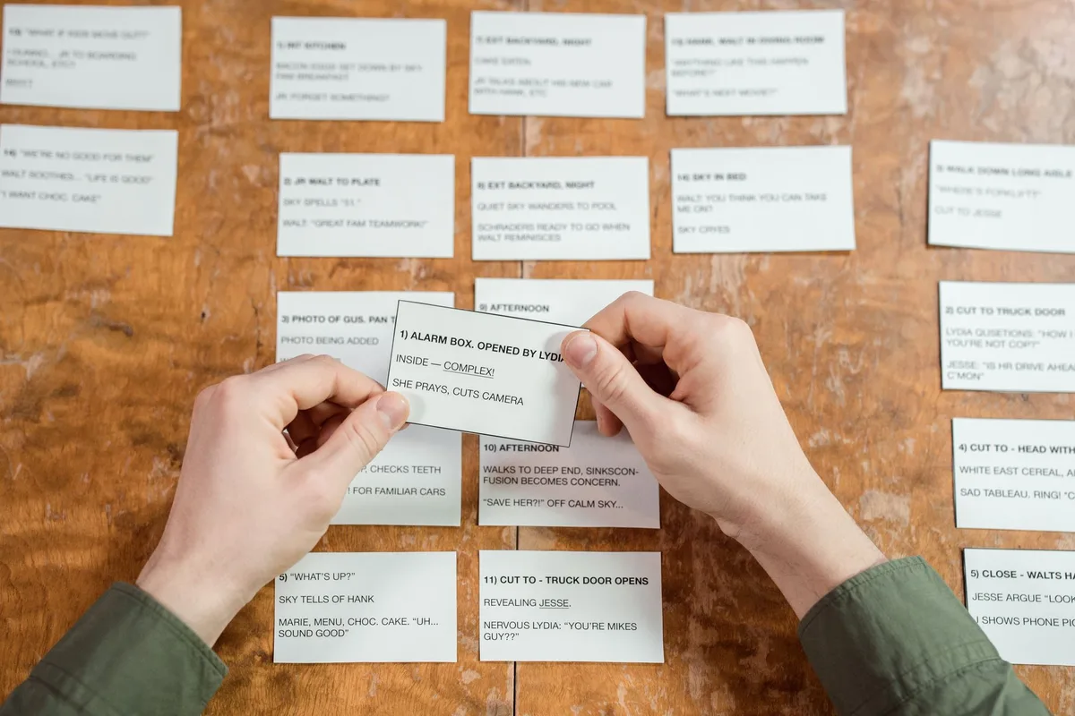 Hands of a collector opening trading card packs at a desk with cards displayed
