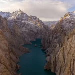 Tourists hiking through mountainous terrain with turquoise lakes and red cliffs in Afghanistan
