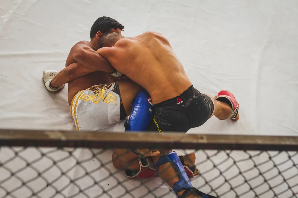 Fighter executing ground control technique in UFC octagon during combat
