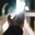 Hands holding generic casino chips with blurred slot machine lights in a casino room