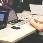 Mesa de trabajo con portátil mostrando un panel genérico, notas y una taza de café