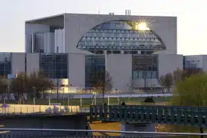 Two anonymous envoys silhouette approaching a government building, briefcases in hand