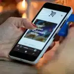 Hand holding phone displaying sports betting app with bonus offer and baseball game