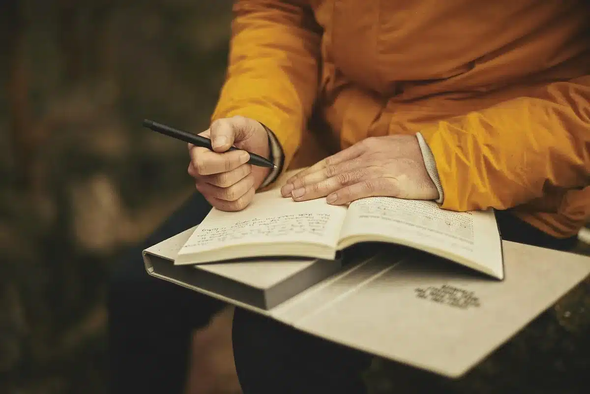Notebook open showing the number 131 with hands pointing and books in the background