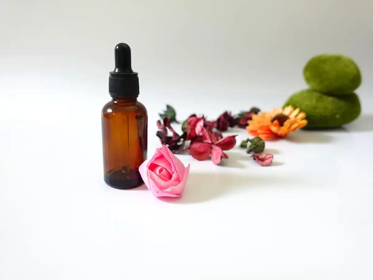 Hands massaging thigh with carrier oil beside small bottles on shelf