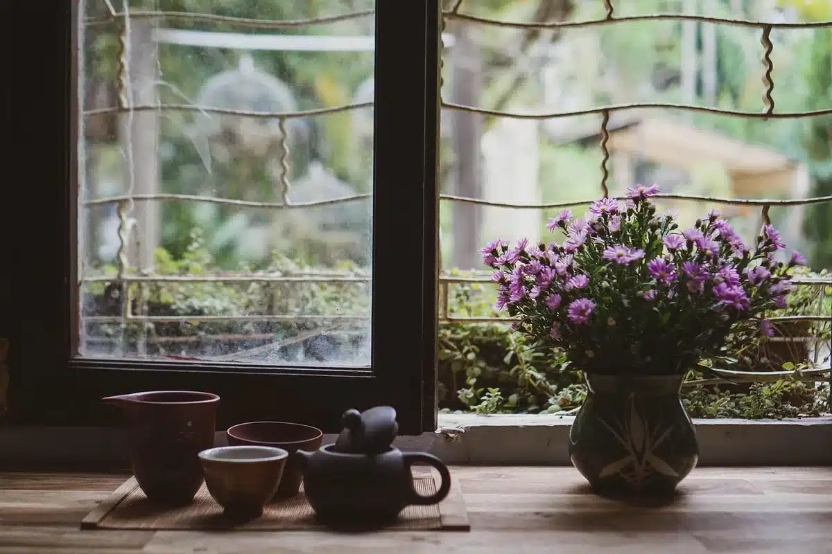 Hands holding a steaming cup and a small plate with fennel, warm kitchen light