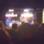 Anonymous crowd applauding at an indoor gala with a stage and projector