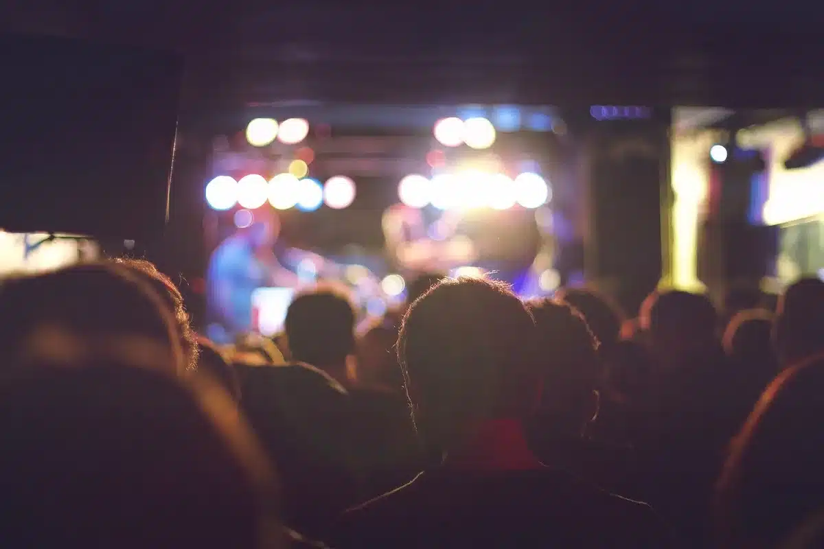 Anonymous crowd applauding at an indoor gala with a stage and projector