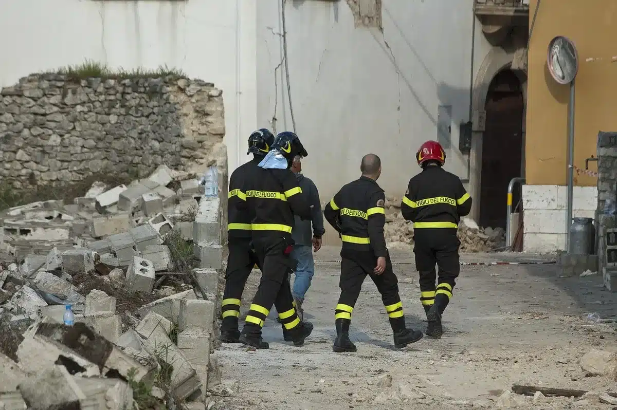 Collapsed mine entrance with rubble and anonymous rescuers at distance