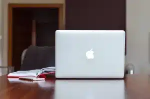 Wireless earbud beside a small Bluetooth speaker on a wooden desk in soft daylight